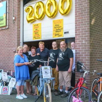 Henny Huisman reikt namens Fietsjes Actie voor Minima in Hoorn 2000e fiets uit